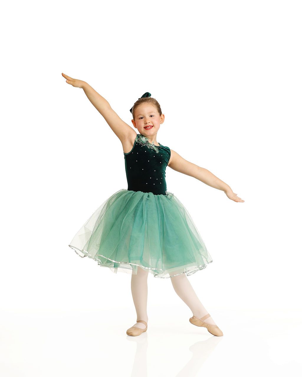 Child in green tutu posing with one arm raised against a white background