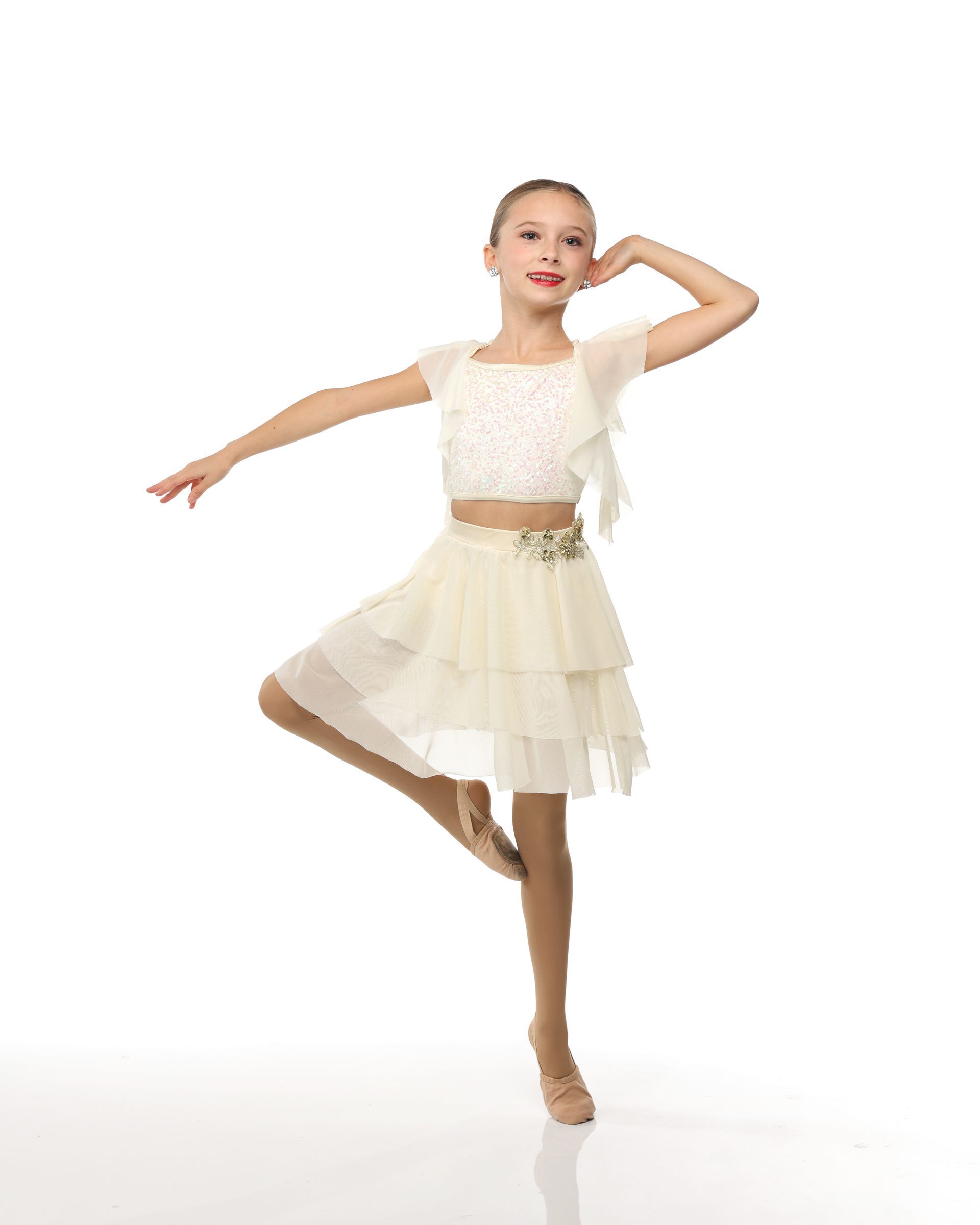 Ballet dancer in a cream costume posing on one leg against a white background
