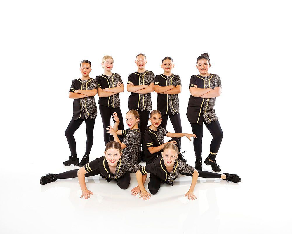 Group of dancers posing in black outfits on a white background