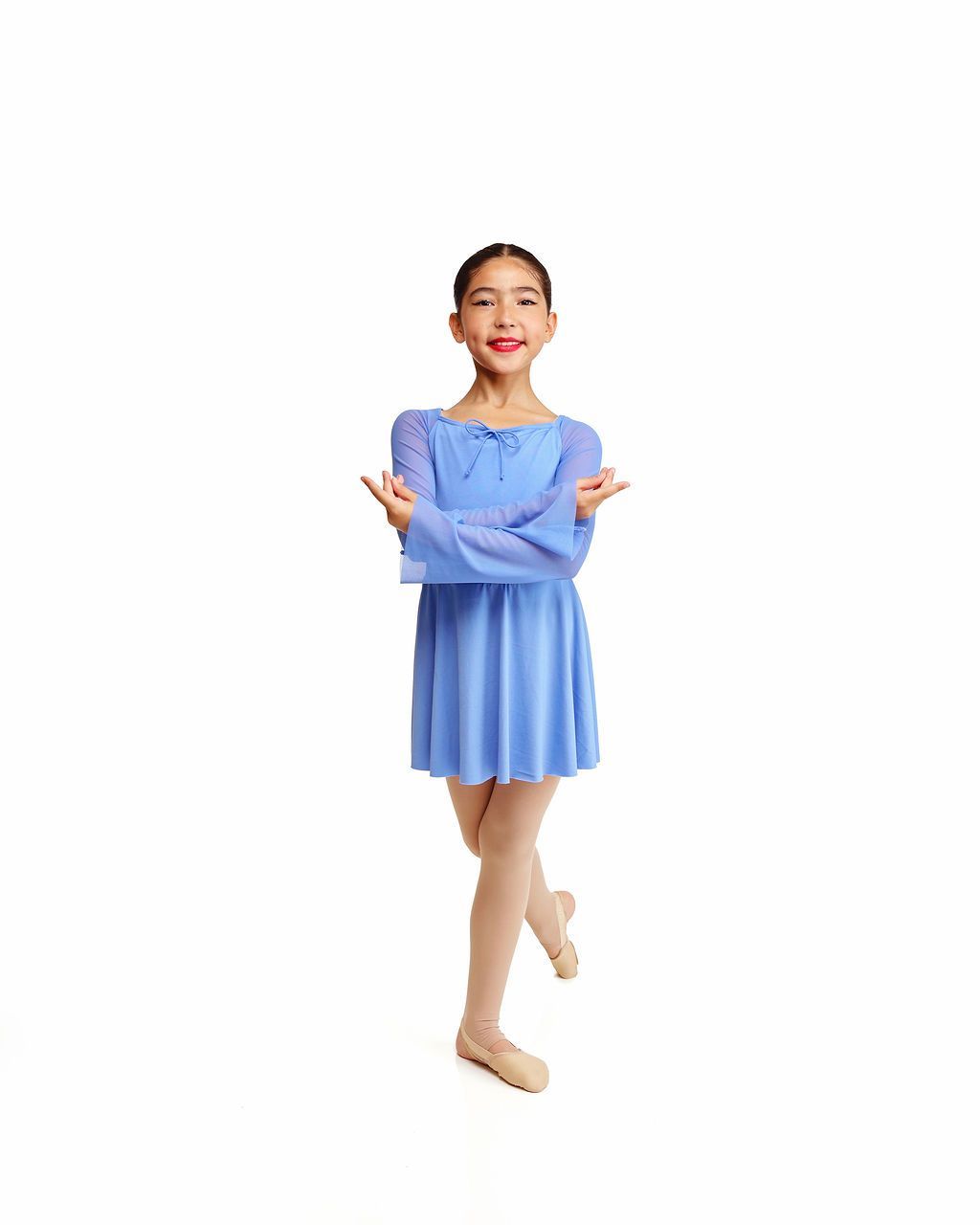 Young ballet dancer in a blue dress posing with arms open against a white background