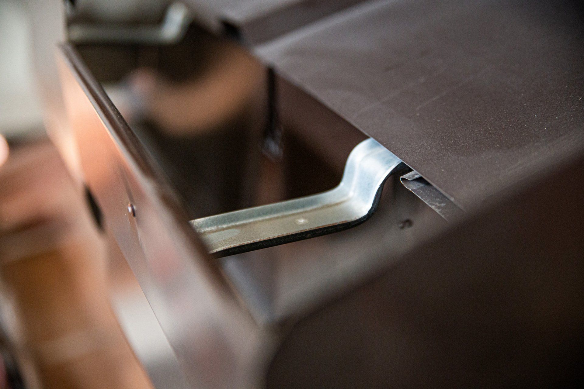Primo piano di un chiavistello metallico o di una chiave inserita in una porta marrone scuro.