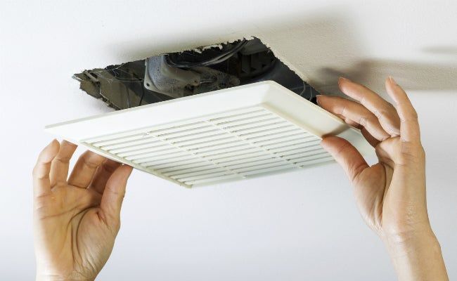 A person is fixing a ceiling fan with their hands.