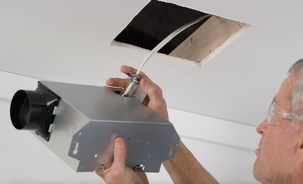 A man is installing a ventilation system in the ceiling.