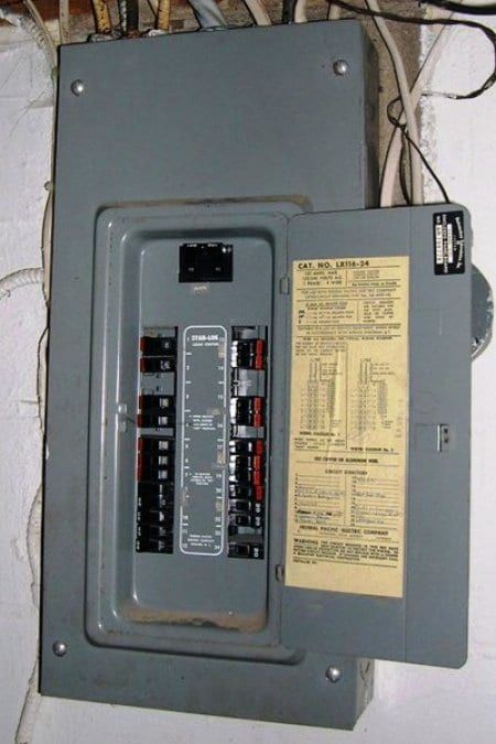 A gray electrical box with a yellow sticker on it