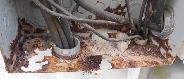 A close up of a rusty box with wires coming out of it.