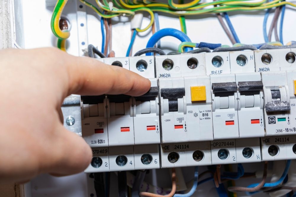 A person is adjusting a circuit breaker in an electrical box.