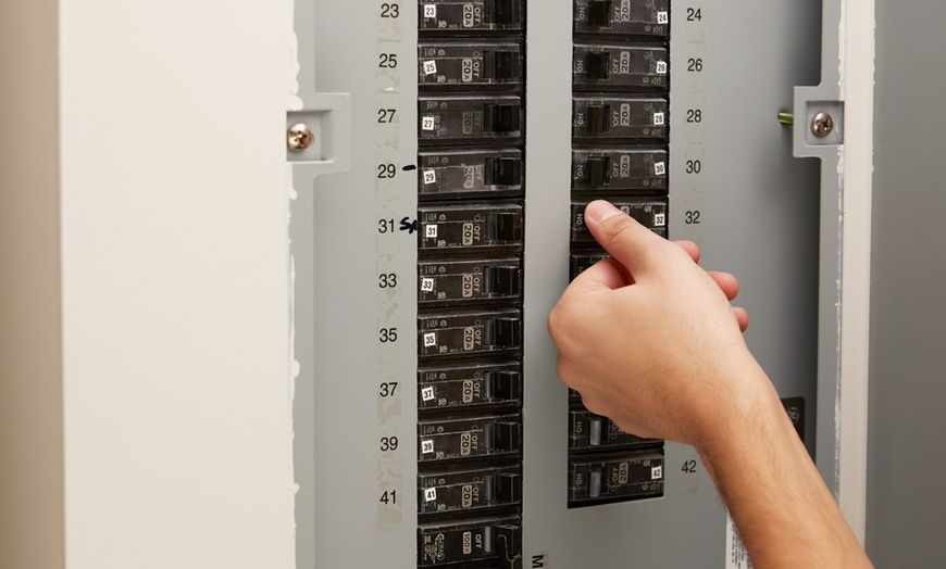 A person is pressing a button on an electrical panel.