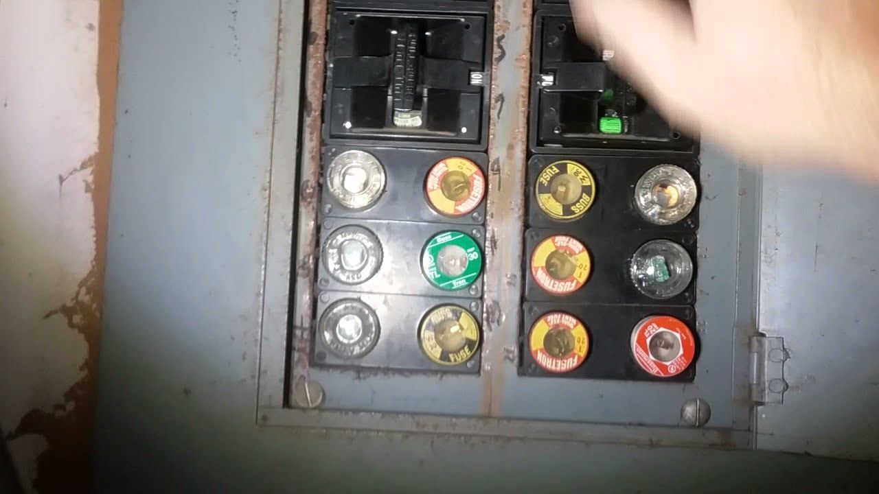 A close up of a person 's hand reaching into a electrical box.