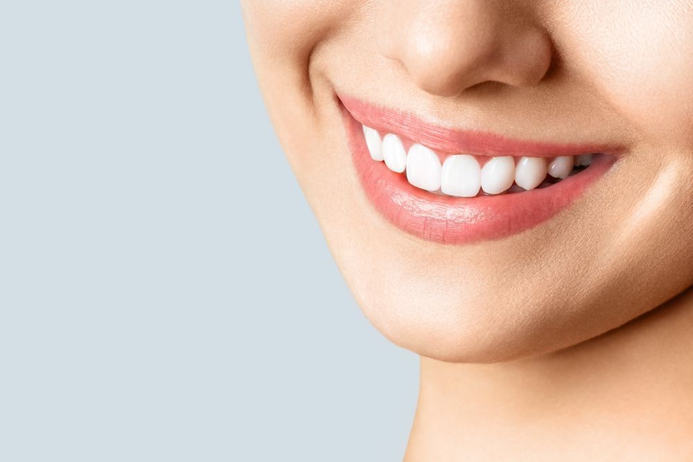 A close up of a woman 's smile with white teeth and pink lips.