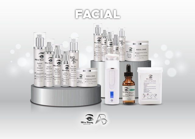 Collection of facial skincare products on a silver platform, set against a blurred light background.