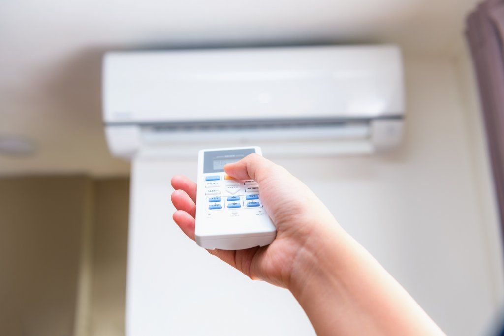persona manejando control remoto de aire acondicionado
