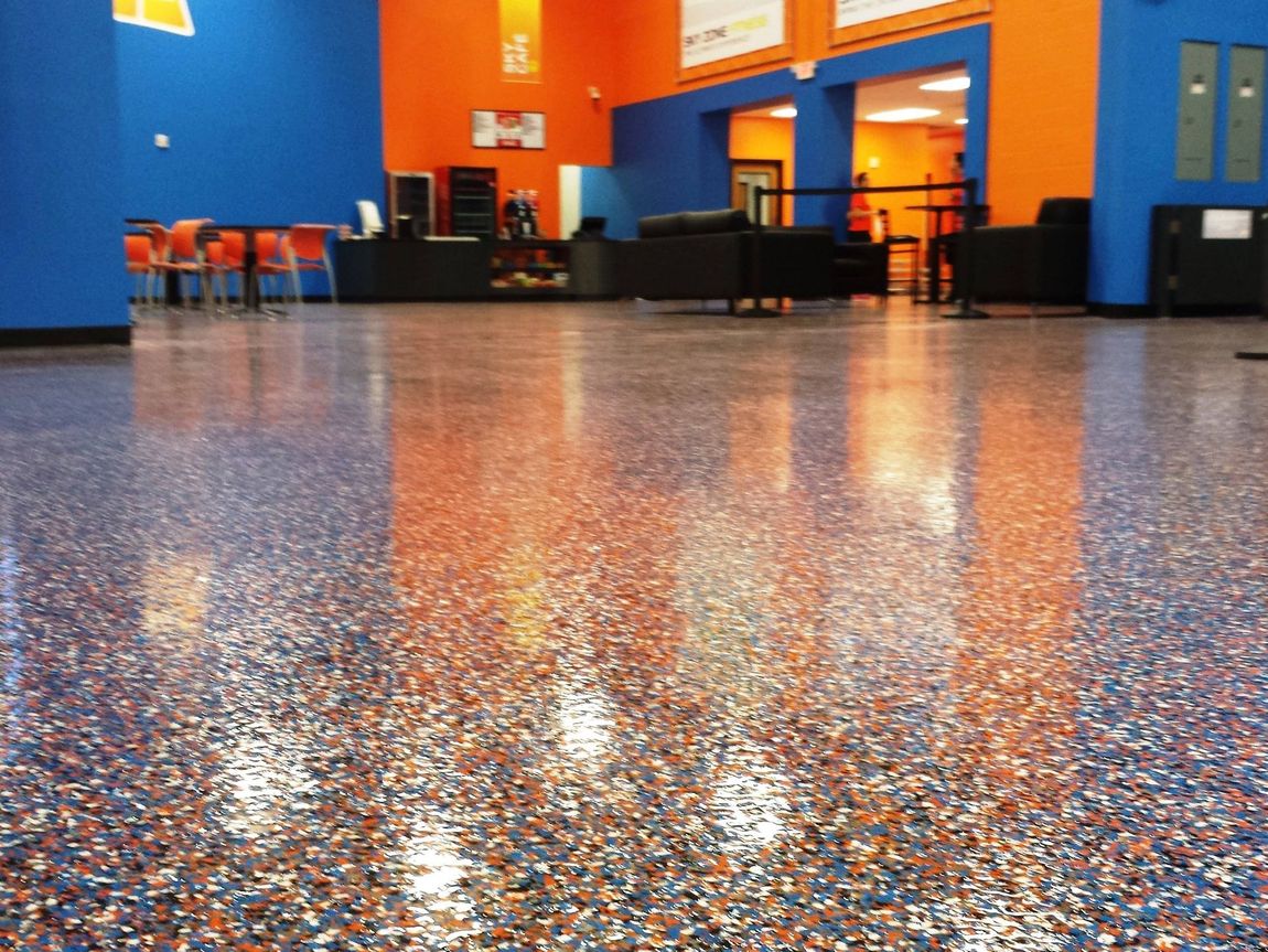 Indoor bowling alley with glossy speckled floor, orange walls, and seating along the back wall.