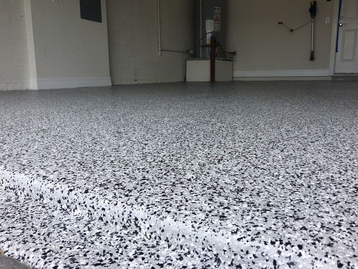 Speckled gray epoxy floor in an empty garage or room with closed doors at the back