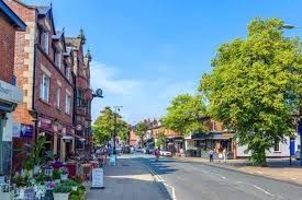 Quiet street with brick shops, trees, and blue sky on a sunny day