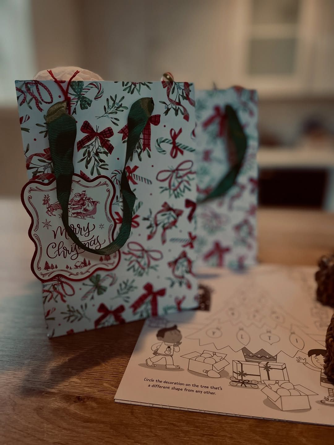 LaplandUK Holiday gift bag with red and green ribbon on a table beside a holiday card.