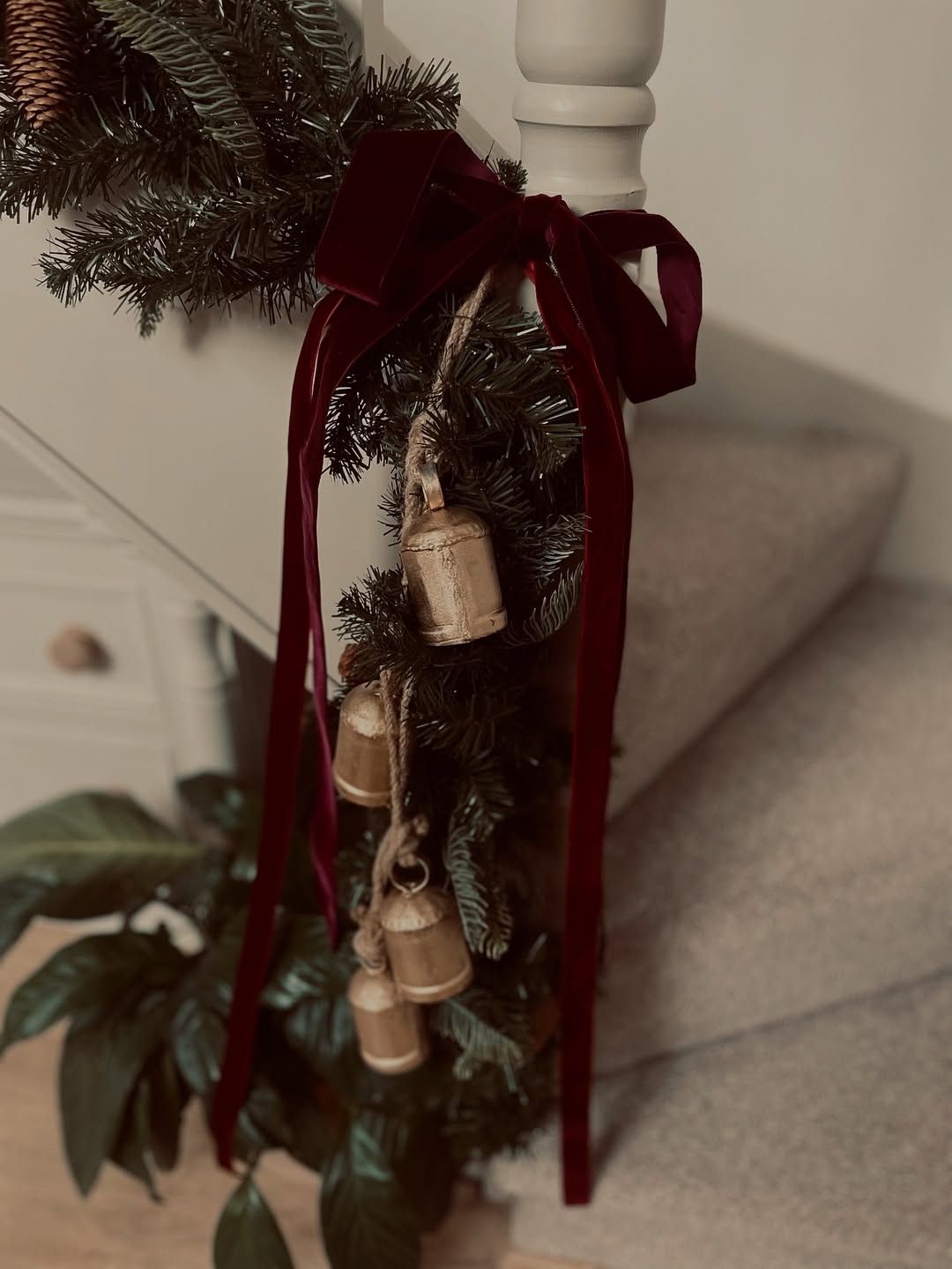 LaplandUK Christmas garland with burgundy ribbons and bells wrapped around a staircase banister