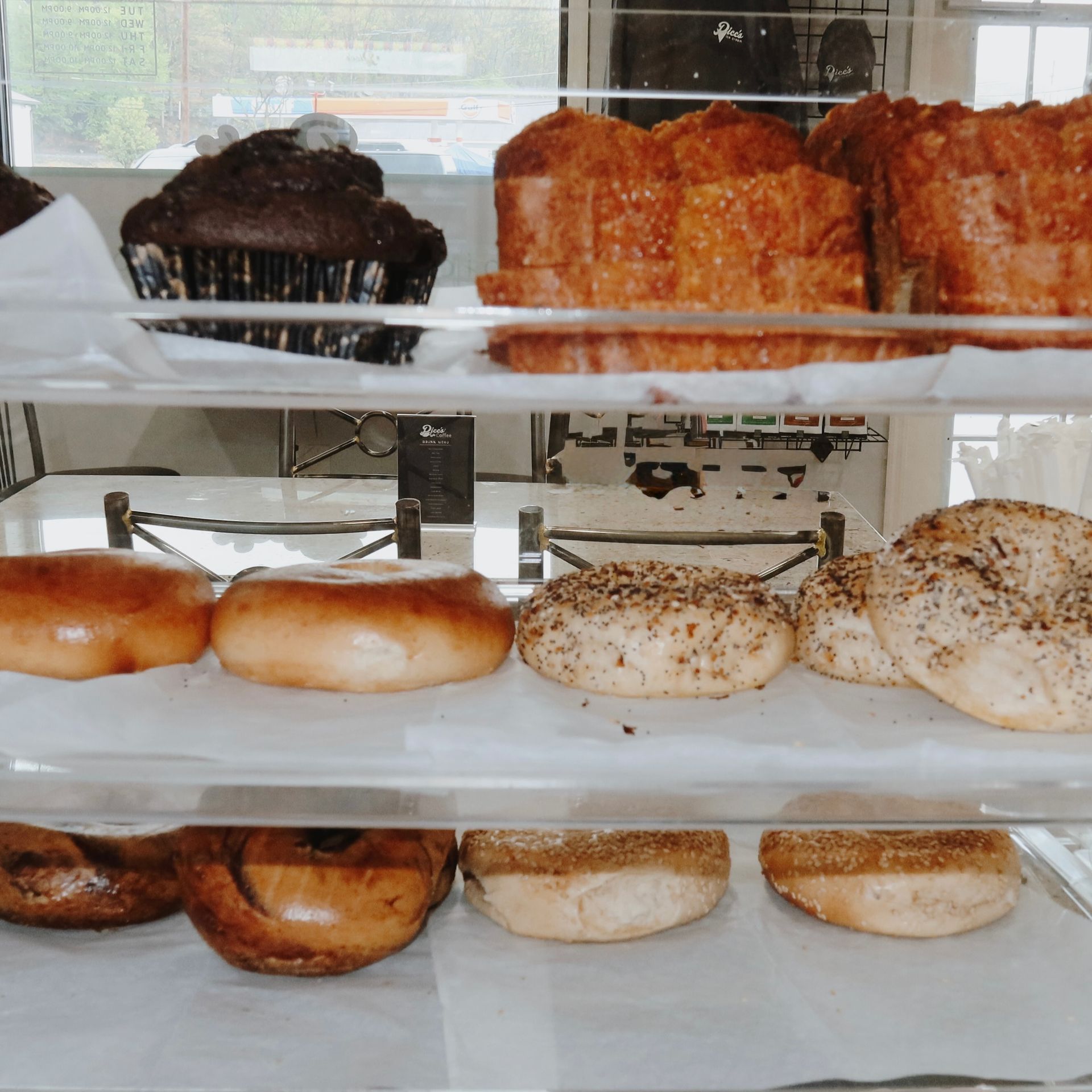 Bakery display case with assorted donuts and pastries on white trays