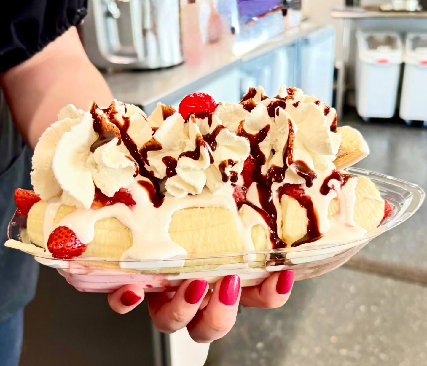Banana split sundae with strawberries, whipped cream, and chocolate drizzle in a clear dish