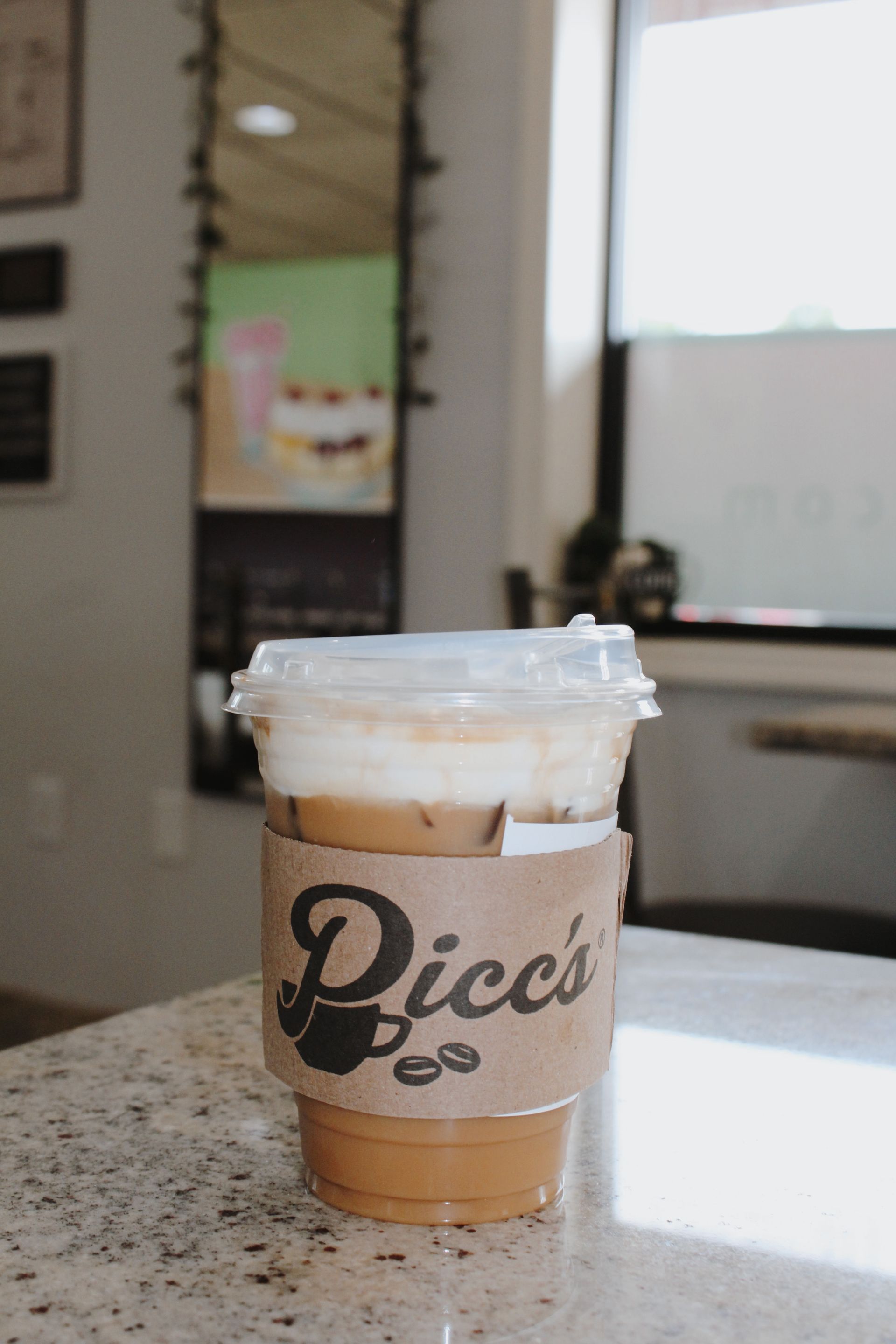 Toasted Marshmallow Latte in a clear plastic cup with a “Picc's” sleeve
