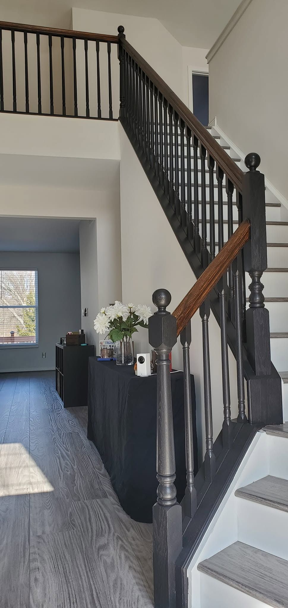 Indoor staircase with dark railings, white walls, and carpeted steps in a home foyer.