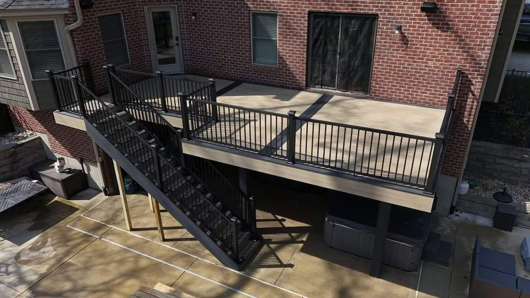 Brick building exterior with black metal fire escape stairs and railing over a paved courtyard.