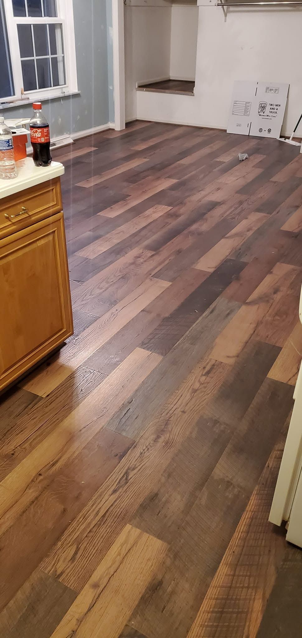 Empty kitchen with dark wood floor and cabinets, white walls, and a doorway in the back.