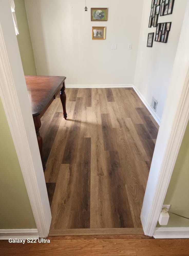Small room with wood-look flooring, a wooden table, and wall art on cream walls