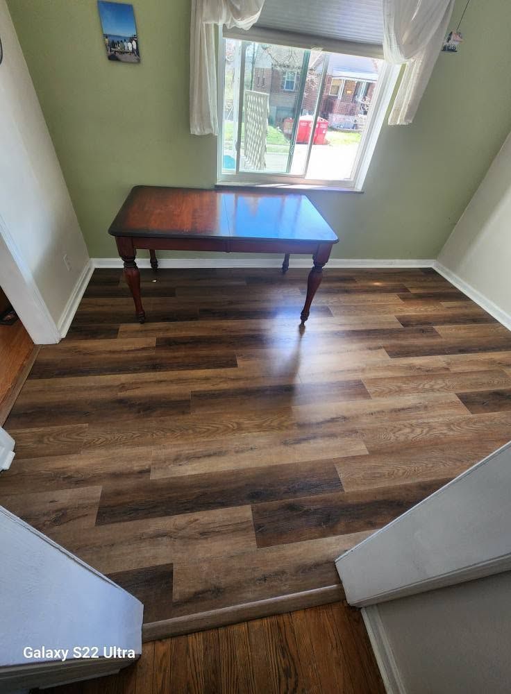 Small room with wood flooring, a dark table by a window, and green walls.