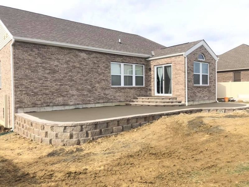 Brick house with a raised concrete patio and dirt yard under construction