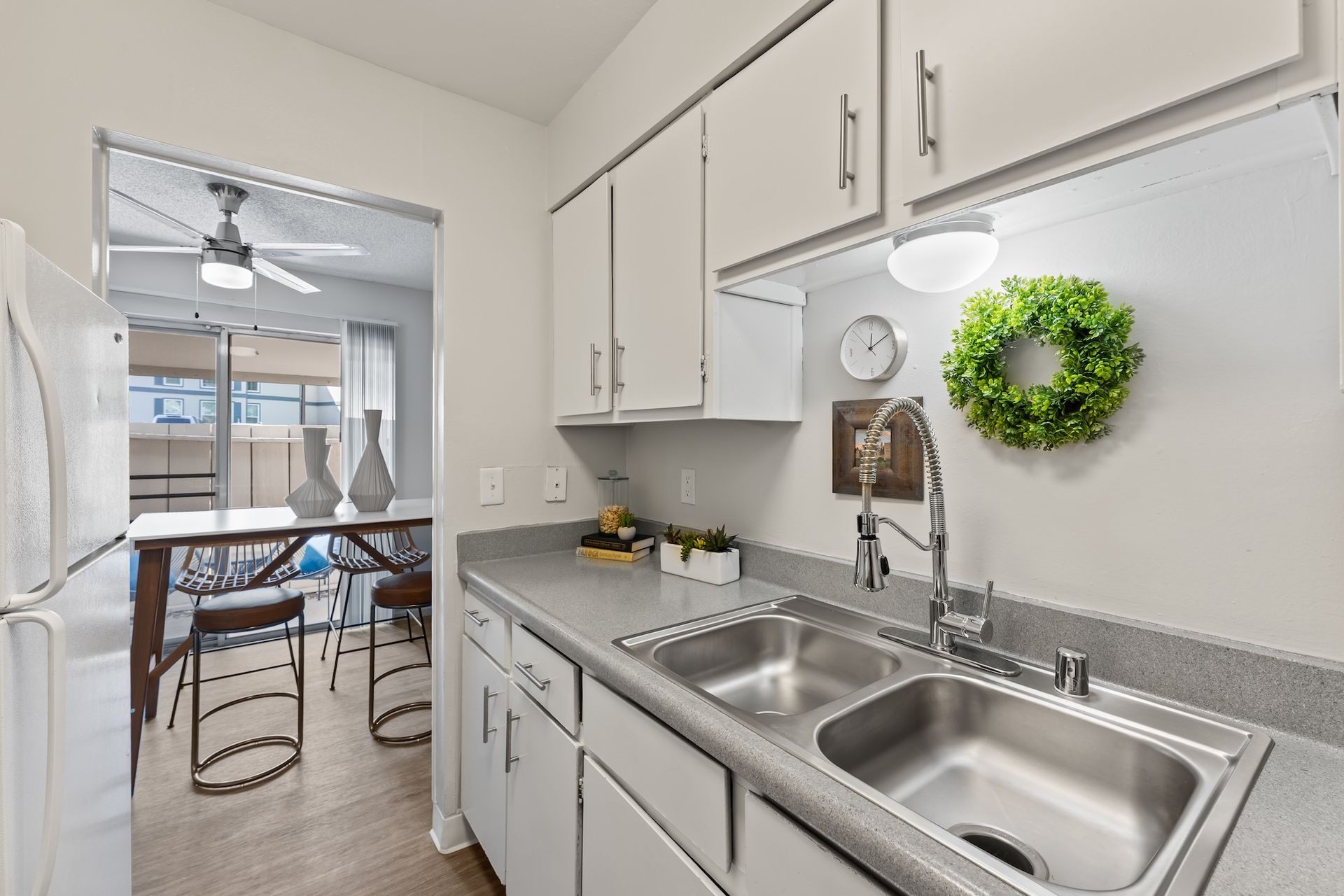 Kitchen with white cabinets, stainless steel sink, and view of dining area.