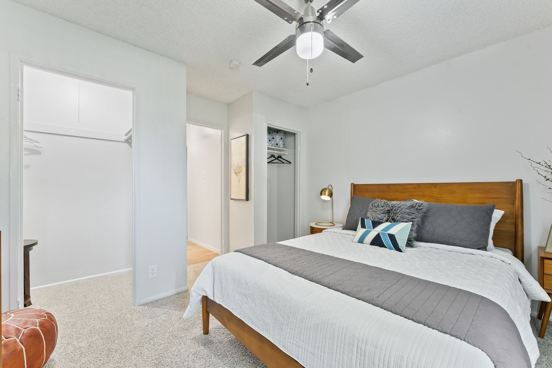Bedroom with wood bed frame, white walls, and walk-in closet.