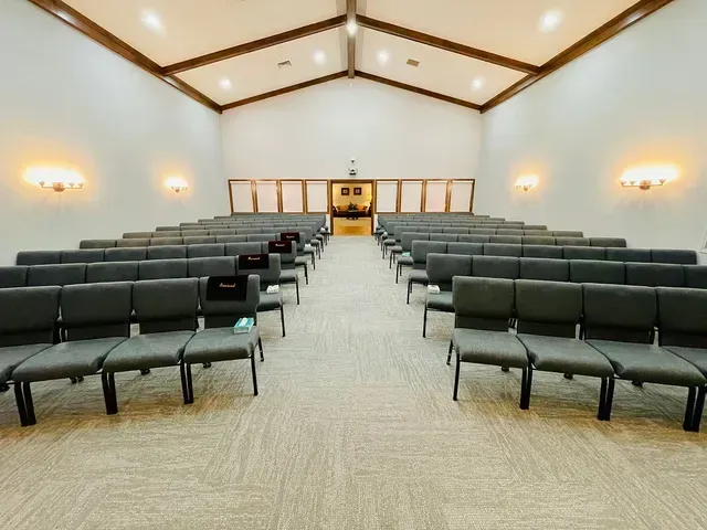 Empty chapel auditorium with rows of dark chairs facing a podium at the front