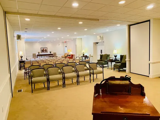 Quiet waiting room with rows of chairs, a desk, and a piano under warm ceiling lights