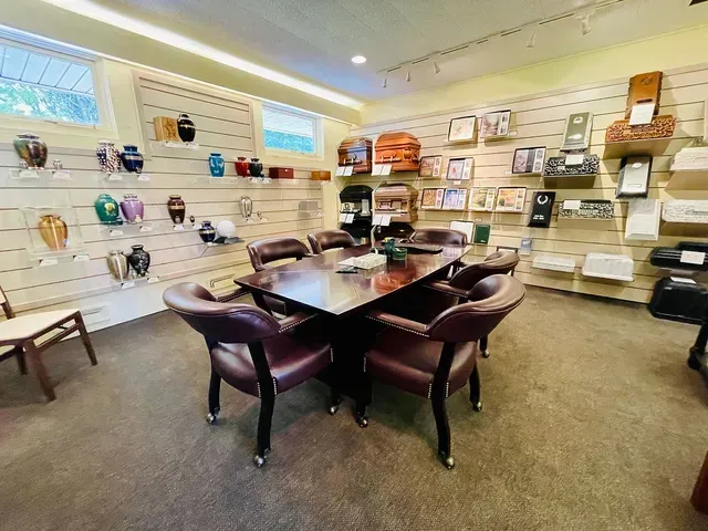 Showroom with a dark wood dining table and chairs, shelves of decorative items along the walls.