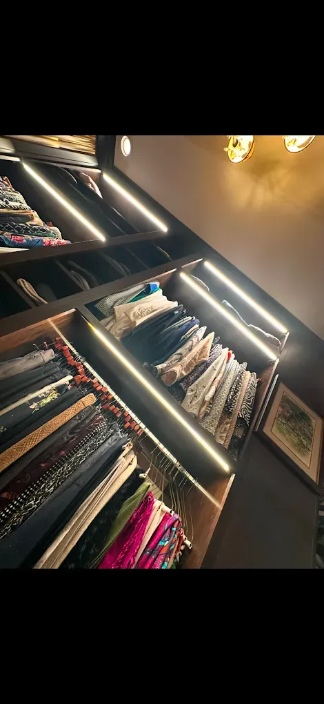 Closet with shelves filled with folded clothing, lit by strips of light.