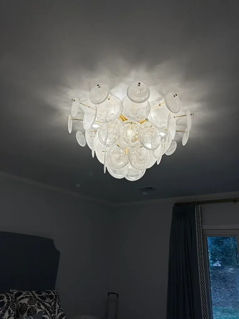 Ceiling light fixture with layered, translucent, disc-shaped elements. Gold hardware.