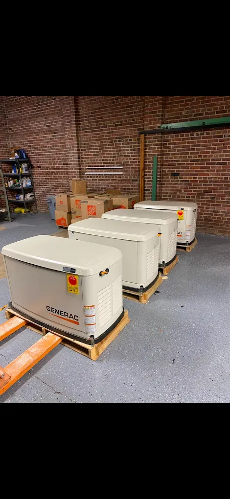 Generators on pallets inside a brick-walled warehouse.