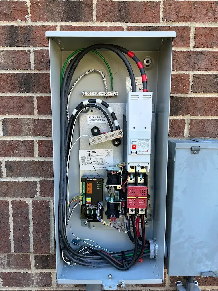 Electrical panel mounted on a brick wall, containing wires, breakers, and other components.