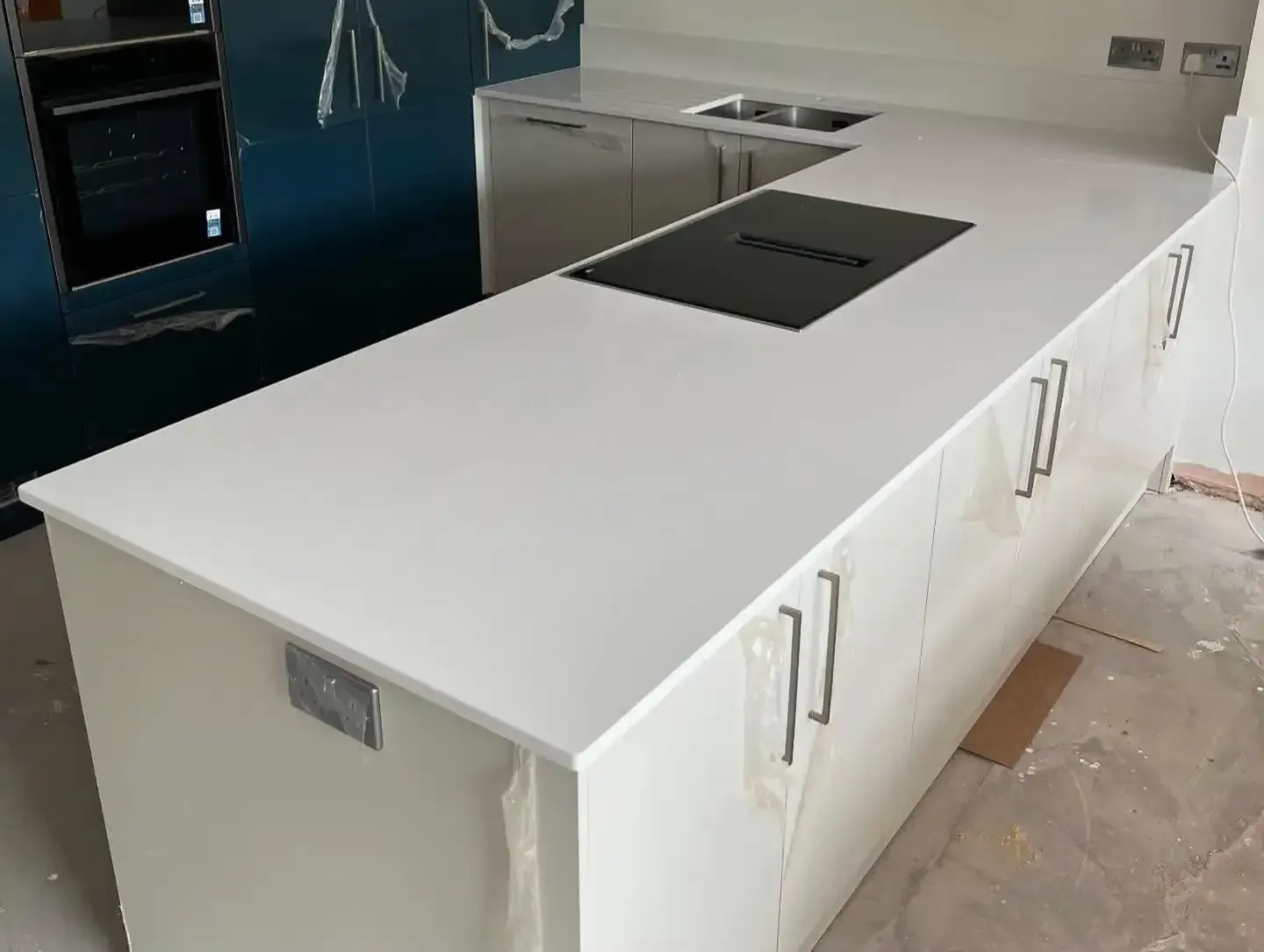 Modern white kitchen island with built-in black cooktop and under-cabinet handles