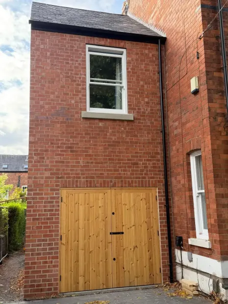 Red brick building with a wooden double door and a window above it
