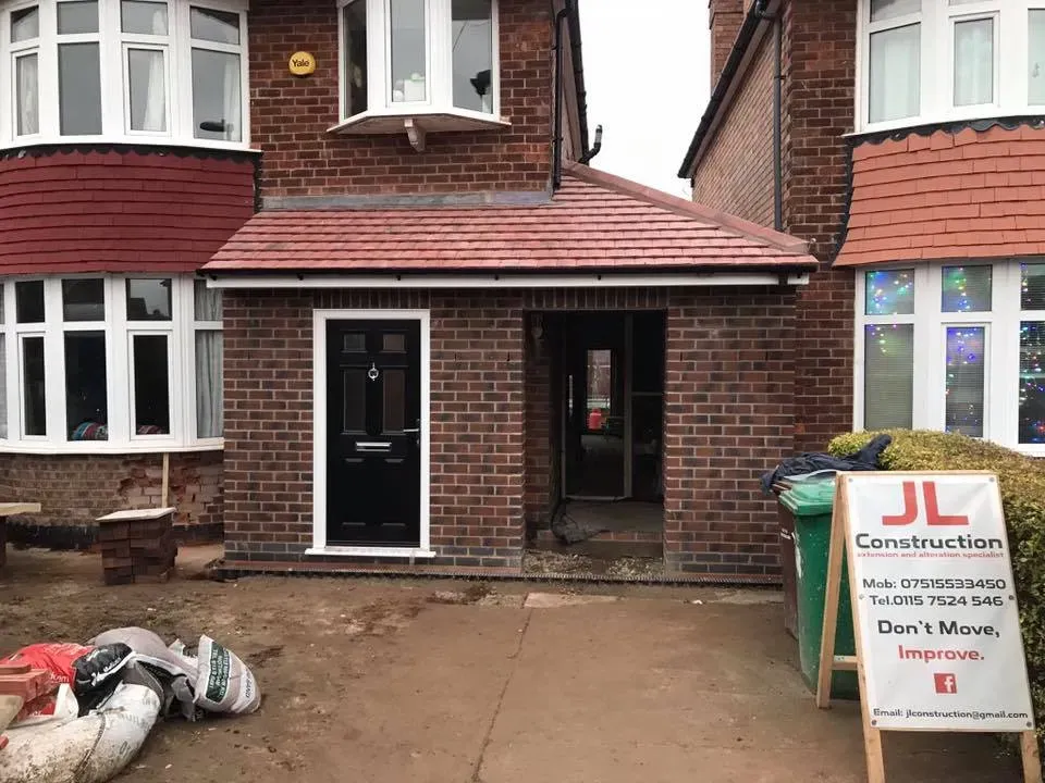 House front with debris on driveway and a construction sign by the entrance