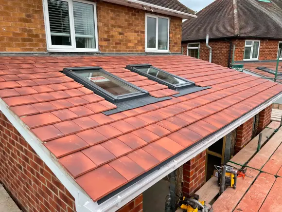 Red-tiled roof with two skylights on a brick house under construction, viewed from above