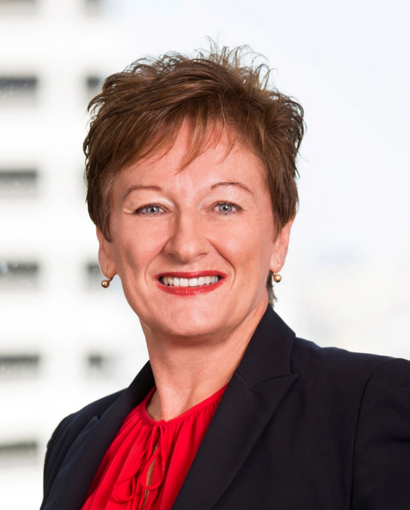 A woman in a suit and red shirt is smiling for the camera.