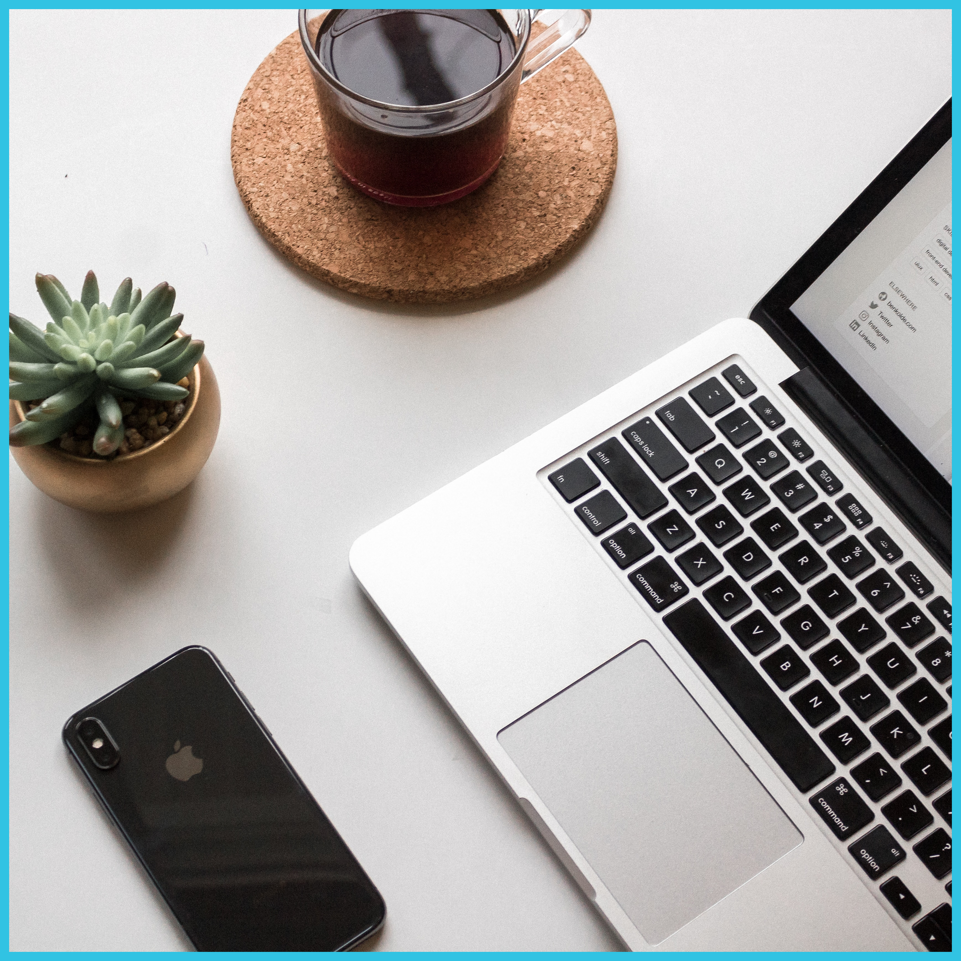 A black iphone sits next to a laptop and a cup of coffee