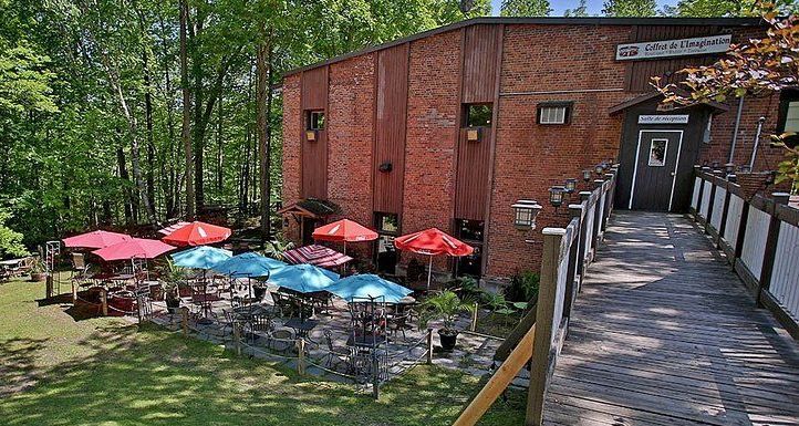 Un bâtiment en briques avec des tables et des parasols devant.