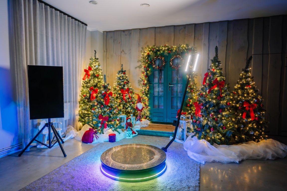 Festive indoor holiday display with three lit Christmas trees and a glowing round platform