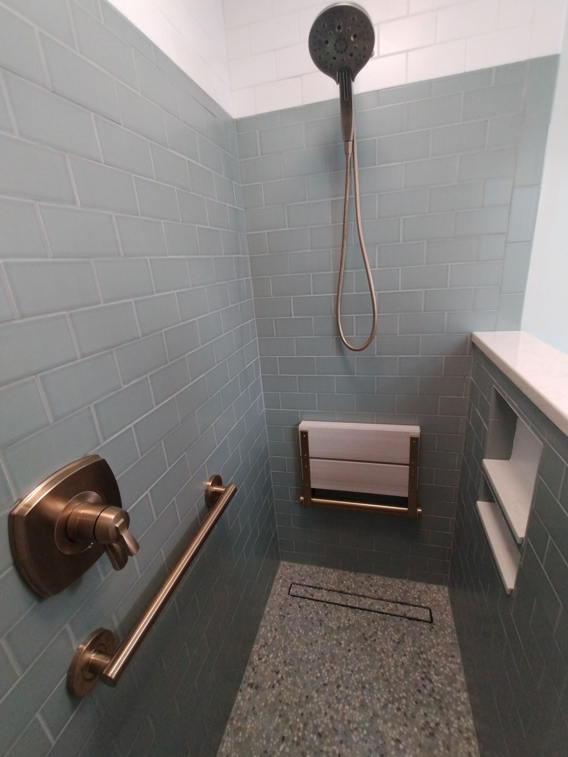 Accessible shower stall with grab bars, handheld shower, shower seat, and non-slip floor for wheelchair users