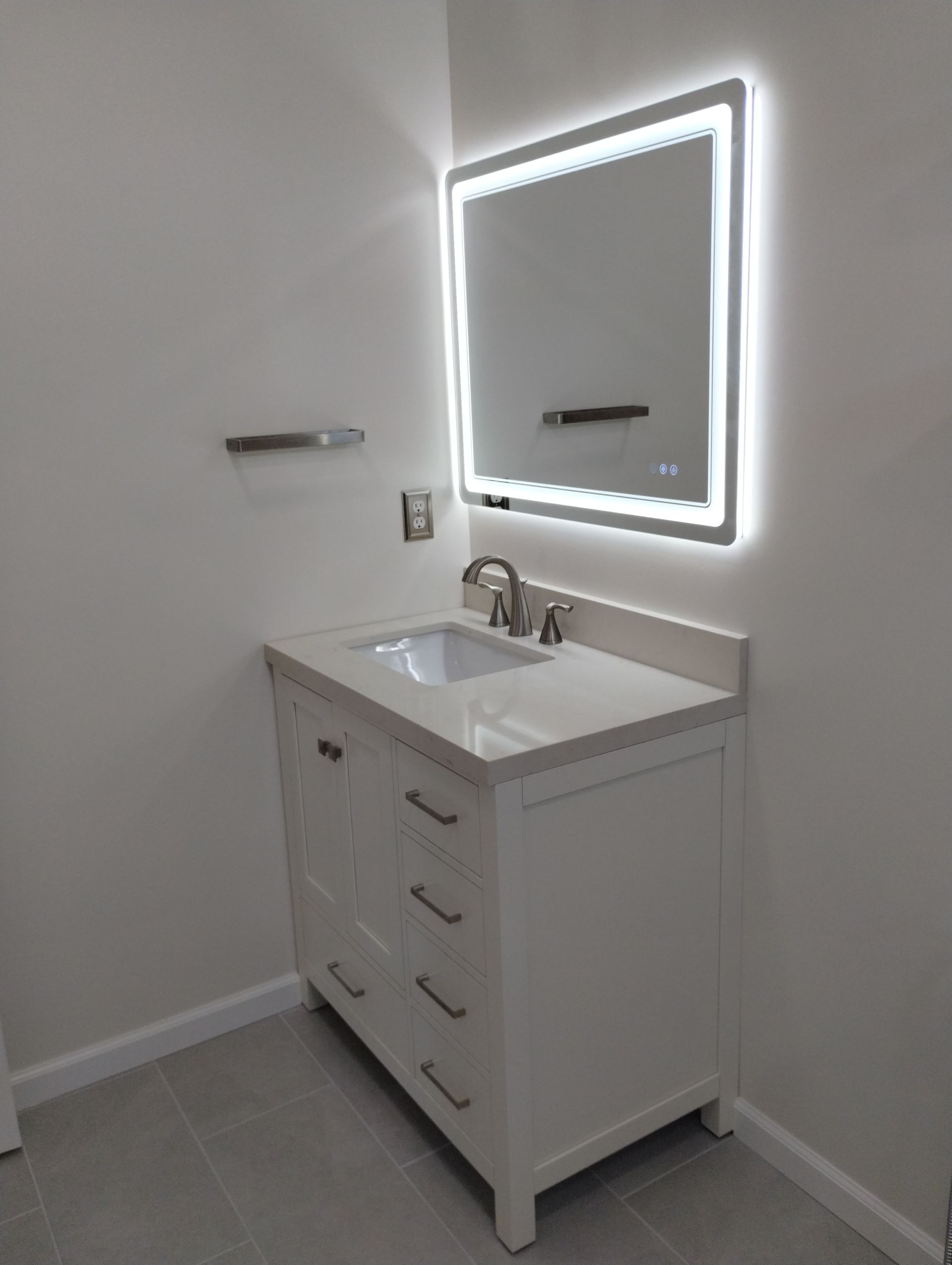 White bathroom vanity with sink and lit mirror in a small modern bathroom