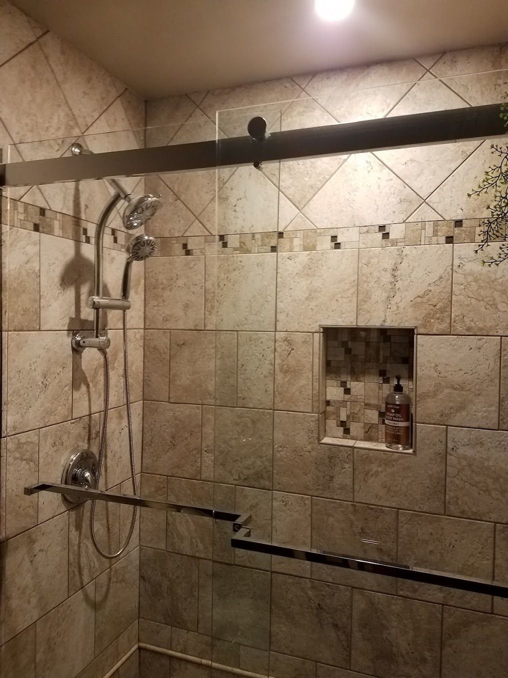 Tiled shower with rainfall and handheld showerheads, black shower curtain rod, and recessed wall shelf