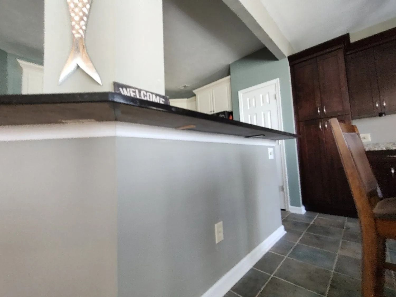 Interior view of a kitchen counter with gray walls, tiled floor, and a doorway to the right